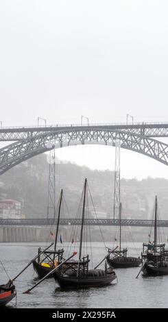 Bateaux rabelos classiques en bois, transportant des tonneaux de vin, amarrés sur le fleuve Douro à Porto, sous le pont en acier Don Luis I dans le carénage de fond Banque D'Images