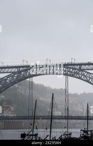 Mâts de bateaux rabelos en bois, transportant des tonneaux de vin, amarrés sur le fleuve Douro à Porto, sous le pont en acier Don Luis I dans le haut-fond Banque D'Images