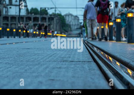 Plan de détail au niveau du sol de la voie ferrée en acier du métro de Porto du pont Dom Luis au crépuscule, avec les lumières sur les poteaux avec les touristes se promenant und Banque D'Images