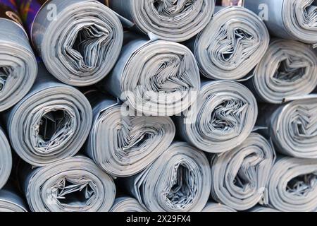 Rouleaux de plastique gris empilés de manière désordonnée, créant un bruit de papier rouleau Banque D'Images