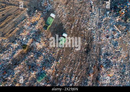 Vue aérienne de haut en bas des camions à ordures qui déchargent une pile de déchets à la décharge. Déversement d'une pile de déchets non triés dans une décharge à ordures. Pollution de l'environnement Banque D'Images