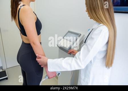 Un praticien de la santé assiste une femme avec un test de composition corporelle à l'aide d'un équipement de pointe. Banque D'Images