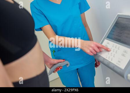 Un praticien de la santé assiste une femme avec un test de composition corporelle à l'aide d'un équipement de pointe. Banque D'Images