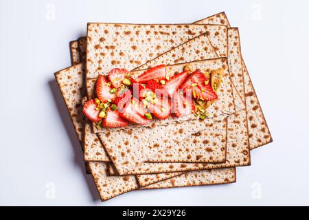 Matzah toast avec beurre d'arachide, fraises et pistaches sur une assiette blanche. Pain traditionnel pour la fête juive de la Pâque. Banque D'Images