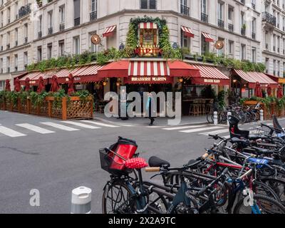 Paris, France, 19 avril 2024 : les touristes visitent le restaurant paris brasserie martin en rouge et décoration florale, vélos debout dans la rue, p Banque D'Images