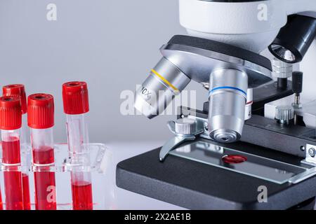 Microscope avec lame contenant des globules rouges. Le microscope est sur une table de laboratoire à côté de quelques tubes de globules rouges. Banque D'Images