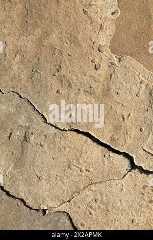 Fissure dans le revêtement en béton d'une vieille maison. Surface rugueuse et irrégulière. Plâtre de ciment sur un mur de briques, texture, fond. Toile de fond ancienne de jaune Banque D'Images