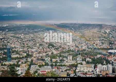 Vue sur la ville de Tbilissi après la pluie, avec un magnifique arc-en-ciel du parc Mtatsminda (Géorgie) Banque D'Images