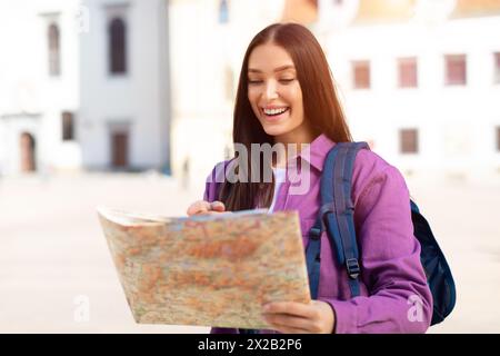 Jeune femme souriante lisant une carte à l'extérieur Banque D'Images