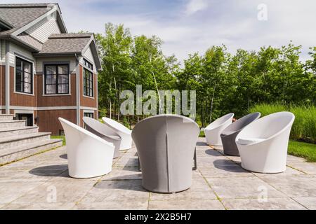 Tissu gris et blanc couverts assis sur chaises de patio dans l'arrière et la lumière des pierres naturelles et bois teint brun et bardeaux de cèdre cl Banque D'Images