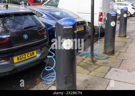 Voitures électriques - une BMW i3 et une Tesla branchées et en charge - à une borne de recharge de réseau public EV fournie par source London. Londres, Angleterre Banque D'Images