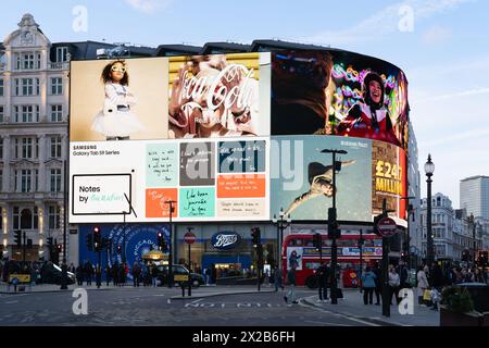 Énormes enseignes au néon et affichage vidéo sur le côté d'un bâtiment à Piccadilly Circus à Londres avec des piétons et un bus londonien devant. Angleterre, Royaume-Uni Banque D'Images