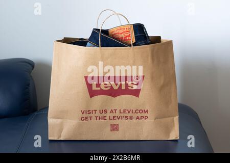 Un sac en papier avec un Jean Levi Strauss & Co à l'intérieur acheté dans un magasin Levi's britannique. Concept : vêtements apportés, sac à provisions durable, logo Levi's. Banque D'Images