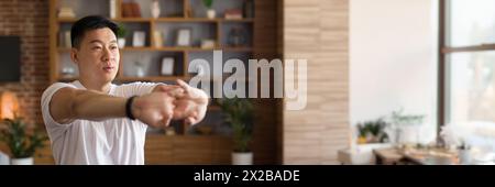 Homme asiatique mature étirant les mains, s'entraînant à la maison Banque D'Images