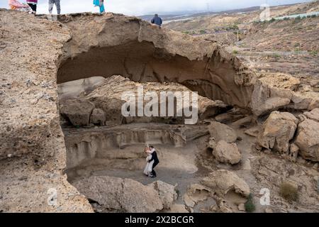 Tenerife, Espagne - 12.05.2023 : couple de jeunes mariés sous roche formant une arche naturelle Arco de Tajao à Tenerife Banque D'Images