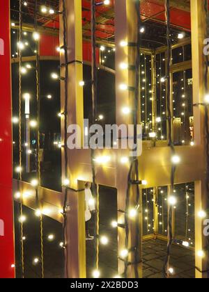 De belles guirlandes décorent le centre-ville. Décorations de rue pour le nouvel an et joyeux Noël. Briller de nombreuses ampoules jaunes et blanches dans l'obscurité. Banque D'Images