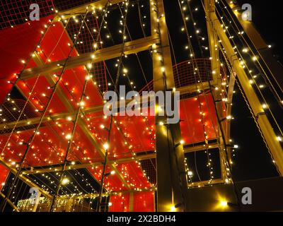 De belles guirlandes décorent le centre-ville. Décorations de rue pour le nouvel an et joyeux Noël. Briller de nombreuses ampoules jaunes et blanches dans l'obscurité. Banque D'Images