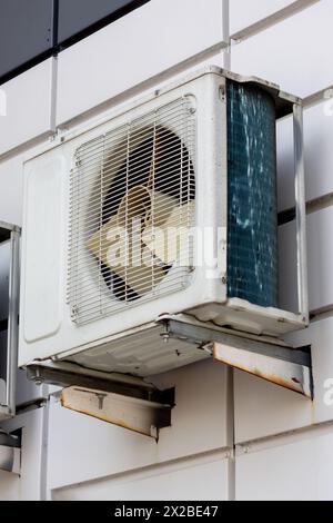 Deux climatiseurs sont fixés sur la façade en brique du bâtiment, l'un à côté d'une fenêtre et l'autre au-dessus d'un rectangle en matériau composite Banque D'Images