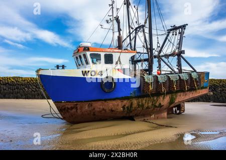 Bateau de pêche bleu amarré dans le port de Folkestone à marée basse avec un ciel bleu profond Banque D'Images