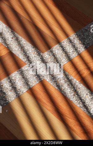 Ombres de lignes obliques qui frappent la surface des tuiles brunes avec des lignes blanches dans l'après-midi Banque D'Images