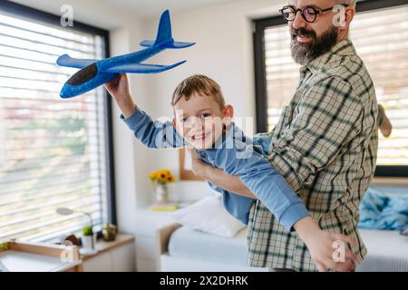 Jouer avec des avions légers en polystyrène. Père et fils ludiques qui lancent et volent des planeurs en mousse. Concept de fête des pères. Banque D'Images