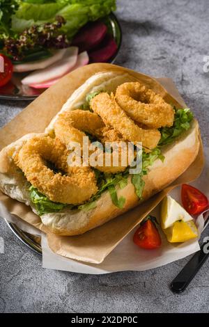 Calmars frit dans du pain avec des légumes verts sur le côté. Sandwich au calmar Banque D'Images