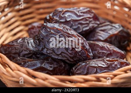 Dattes medjool séchées dans un bol en rotin en bois gros plan. Dessert arabe. Concept de nourriture traditionnelle Ramadan. Banque D'Images