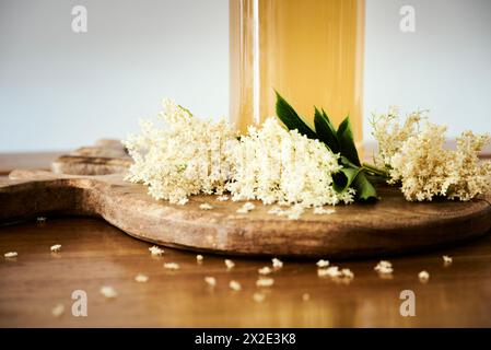 Fleur de sureau fraîche maison cordial gros plan avec de petites fleurs blanches et un détail de bouteille avec la boisson sucrée. Arôme ou vibrations printanières sucrées Banque D'Images