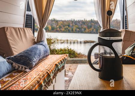 Vie de van confortable avec café presse française et vue sur le lac serein Banque D'Images