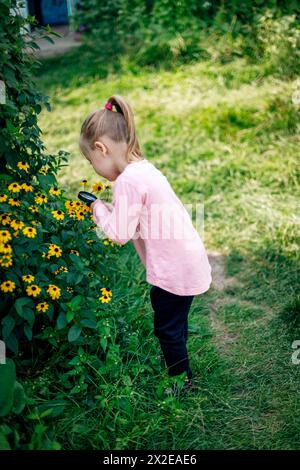 Un enfant examine une fleur sous une loupe Banque D'Images