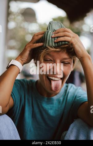 Gros plan d'une femme ludique couvrant les yeux avec un chapeau en tricot Banque D'Images