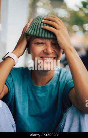 Heureuse femme riante tirant sa casquette sur ses yeux. Idiot. Banque D'Images