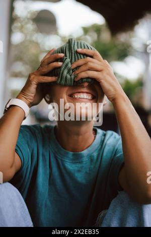 Gros plan d'une femme ludique couvrant les yeux avec un chapeau en tricot Banque D'Images