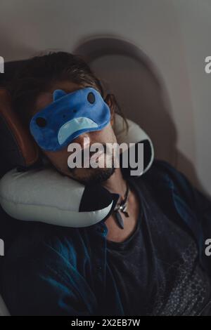 Homme dort dans un avion pendant le vol portant un masque de sommeil. Banque D'Images