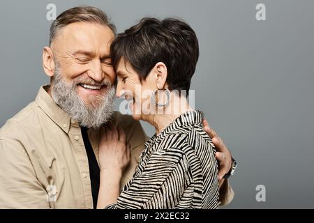 Un homme et une femme d'âge moyen, habillés avec élégance, enveloppés dans une tendresse étreinte dans un cadre de studio. Banque D'Images