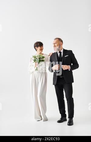 Une mariée d'âge moyen et marié en tenue de mariage célébrant leur journée spéciale dans un cadre de studio. Banque D'Images