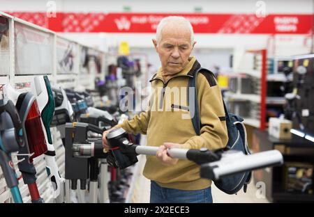 Senor homme retraité achetant aspirateur droit dans la salle d'exposition du magasin d'appareils électriques Banque D'Images