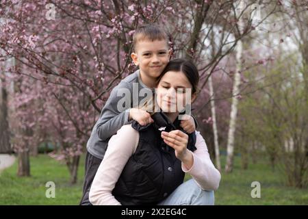 Fils donne à sa mère une petite fleur de cerisier en fleur au printemps Banque D'Images