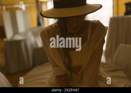 Femme élégante à la mode portant une robe blanche d'été, chapeau de paille, posant dans un intérieur boho élégant. Copier, espace vide pour le texte Banque D'Images