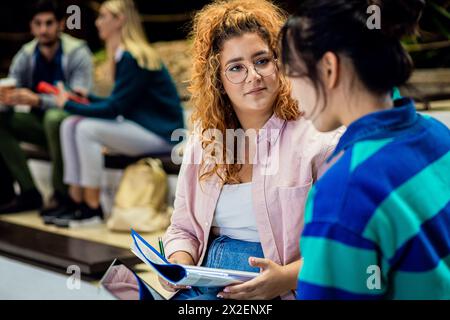 Groupe diversifié d'étudiants se trouvant dans l'apprentissage du campus ensemble. Banque D'Images