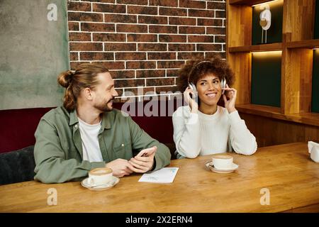 Une femme et un homme afro-américains ont pris part à des conversations téléphoniques alors qu'ils étaient assis à une table de café. Banque D'Images