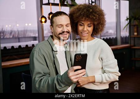 Un homme et une femme afro-américaine pris dans un téléphone portable dans un café moderne. Banque D'Images