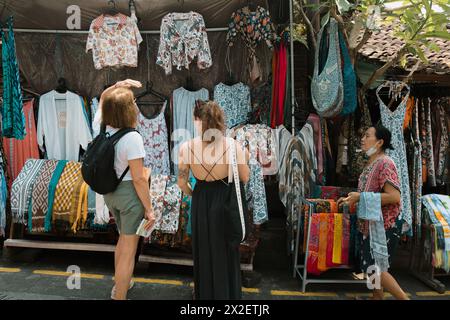 Deux femmes touristes faisaient des négociations avec le vendeur local dans le marché traditionnel d'Ubud. Photographie de rue. Banque D'Images