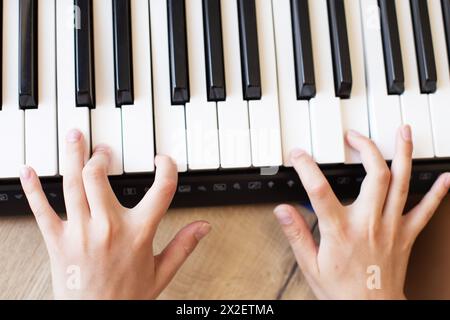 Gros plan vue du dessus photo d'un petit enfant les mains de garçon d'étudiant joue, apprend et pratique le piano. Accords de piano dans la clé. Passe-temps de musique et Banque D'Images