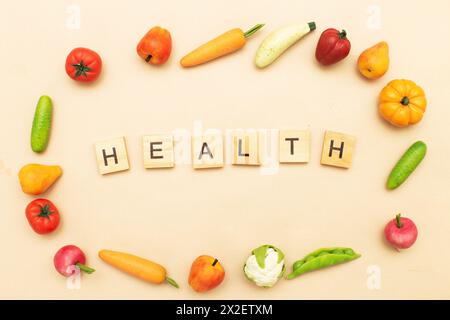 Différents produits alimentaires sains sur un fond beige. Mot santé fait par des cubes en bois et de nombreux fruits et légumes Banque D'Images