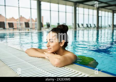 Une femme brune en maillot de bain se relaxant dans une piscine, profitant d'un moment de paix et de rafraîchissement. Banque D'Images