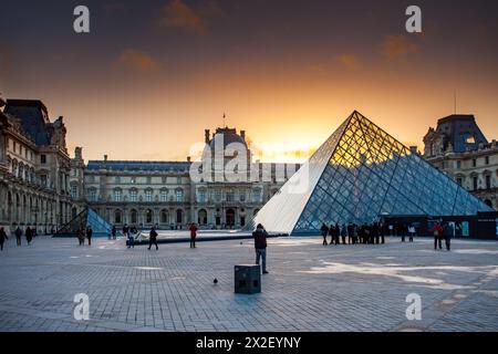 'Coucher de soleil sur le musée du Louvre avec pyramide de verre emblématique. Banque D'Images