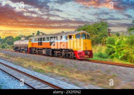 Locomotive diesel, augmentant la vitesse et laissant un panache de fumée, voyage le long de la route ferroviaire transportant un char accroché avec liq solitaire et solitaire Banque D'Images