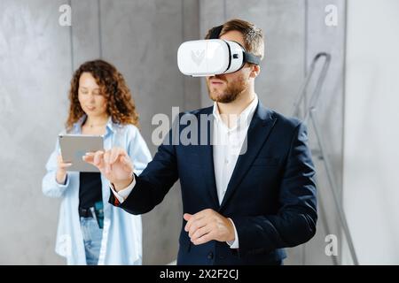 Homme client portant des lunettes VR imaginant l'avenir de l'intérieur debout avec le concepteur sur le chantier de construction. Le concept de réparation sur un design moderne Banque D'Images