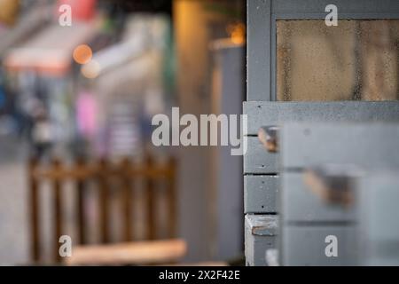 Les jours de pluie s'envolent. Vue imprenable sur la rue avec éléments de mobilier de café. Gouttes de pluie sur différentes surfaces. Mise au point sélective. Banque D'Images